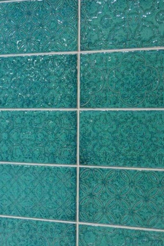 Turquoise tile with floral designs and a textured, high-floss surface